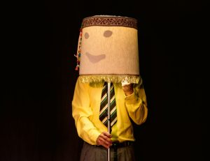 Mensch mit Lampenschirm vorm Kopf