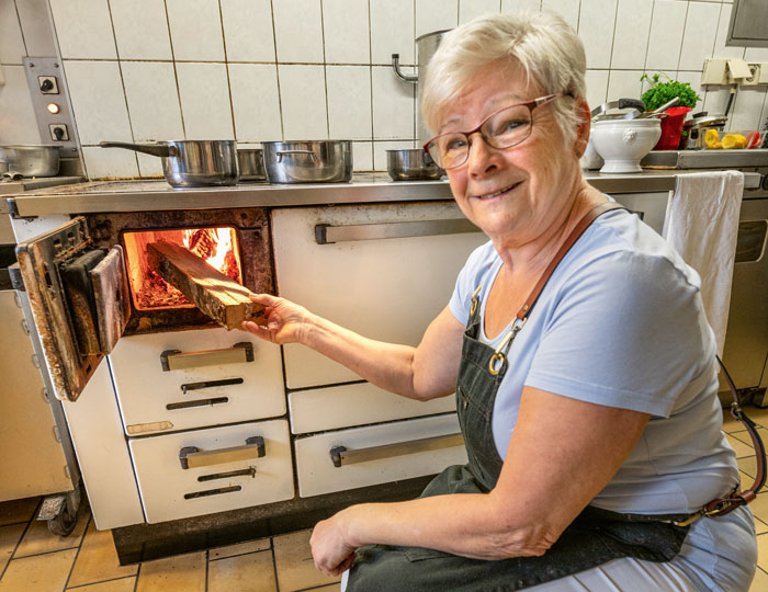 Elisabeth Brucker freurt mit Holz den Ofen an