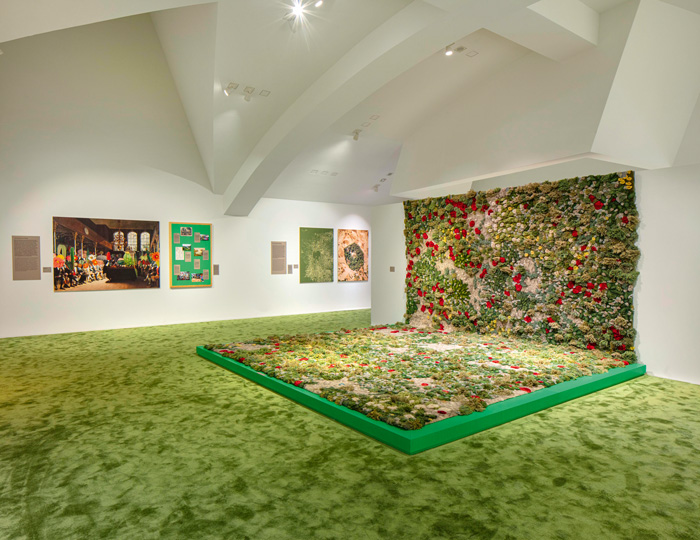 Ein Ausstellungsraum mit grünem Boden und einer farbenreichen Blumenwand