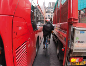 Radfahrer der durch rote Buse fährt