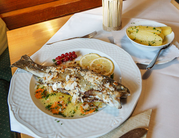 Ein Gedeckter Tisch mit einer Forelle mit Mandeln im Teller