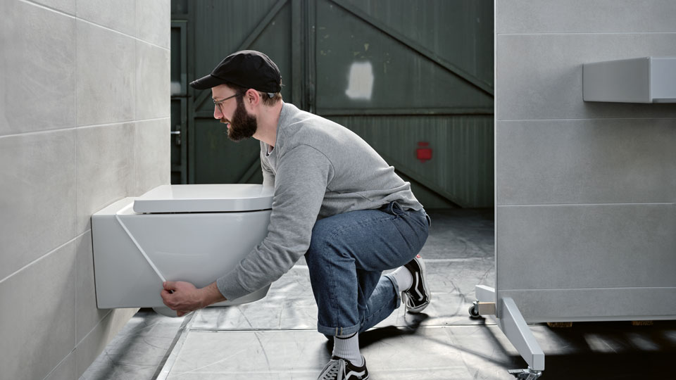 Auf dem Bild ist ein Mann der einen Fugenring von eezee an eine Toilette anbringt
