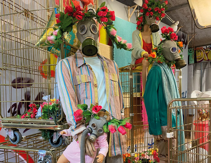 Schaufensterpuppen im Kaufhaus Sluiz, die eine Gasmaske tragen und von roten Rosen umgeben sind