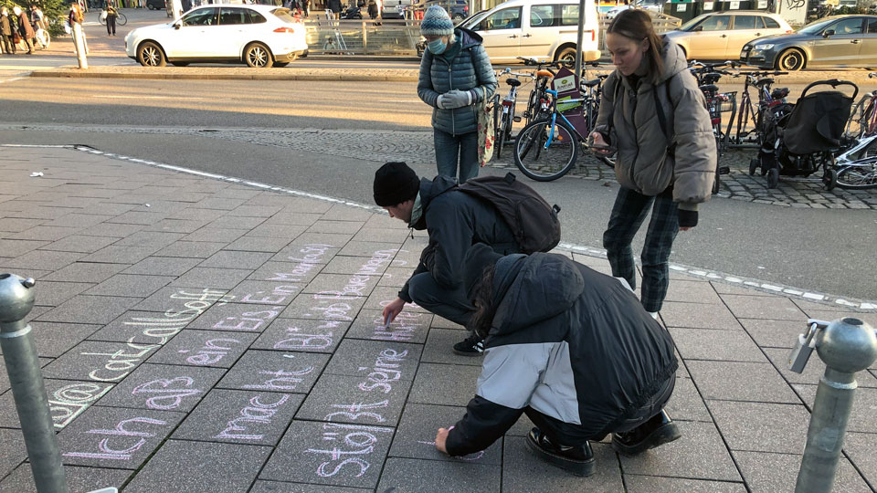 Menschen malen mit Kreide auf den Boden