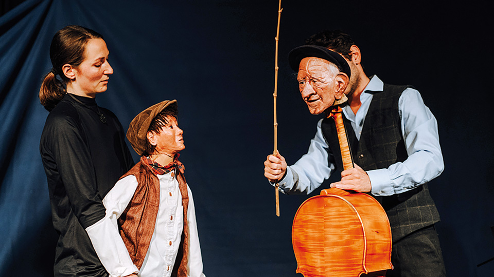 Ein Mann und eine Frau die auf einer Bühne ein Puppenspiel veranstalten