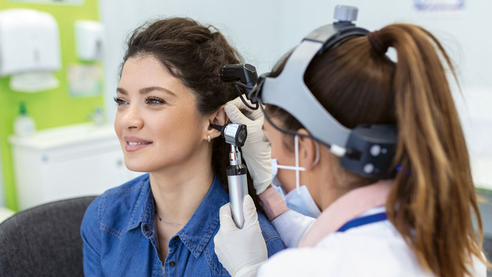 Ärztin untersucht Ohr von Patientin