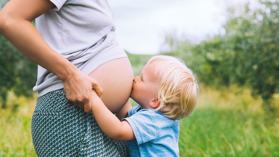 Kind küsst Schwangerschaftsbauch