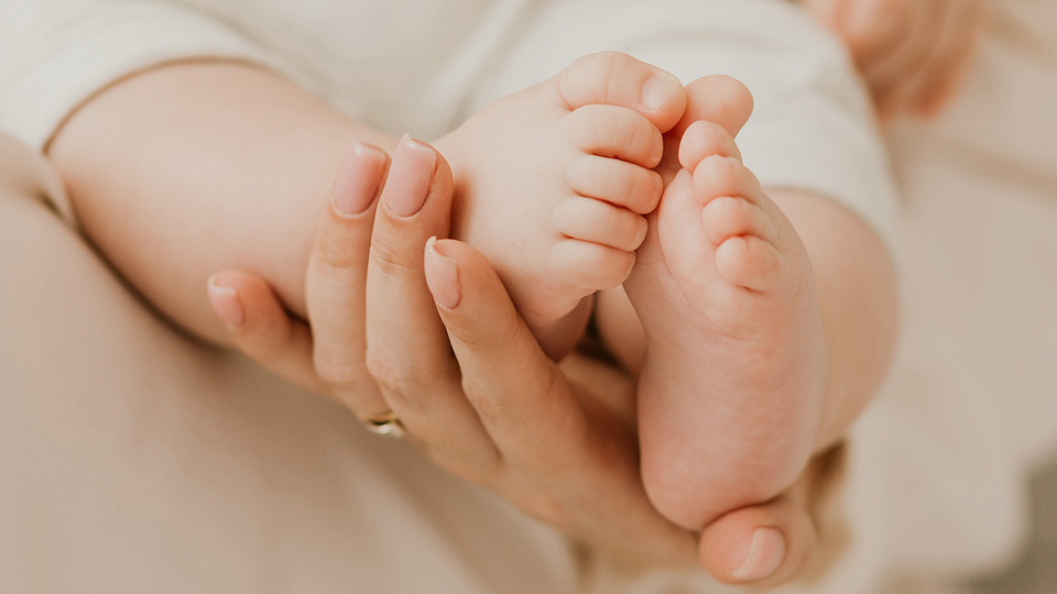 Mutterhände und Babyfüße