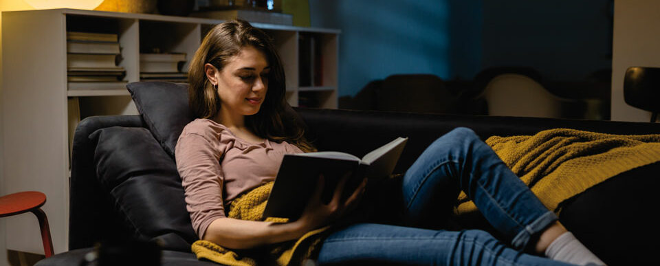 Frau auf der Couch lesend