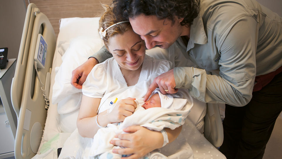 Mutter und Vater mit ihrem Neugeborenen im Krankenhauszimmer