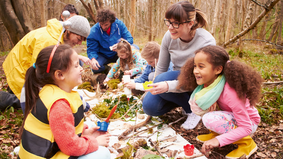 Kinder und Erwachsene beim Spielen im Wald