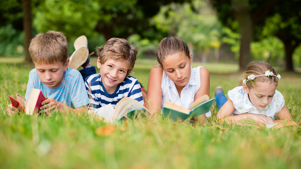 Kinder lesen auf Wiese