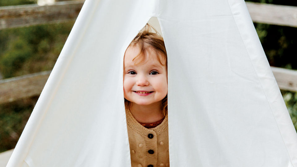 kleines Mädchen, dass sich in einem Zelt versteckt